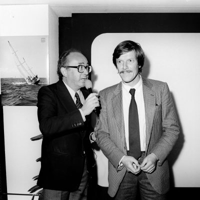 1980 - Ambrogio Fogar intervistato in occasione del 20° Salone Nautico di Genova. Per celebrare la ventesima edizione, l'emblema del Salone, sormontato dalla croce di San Giorgio è esposto in tutte le vetrine della città